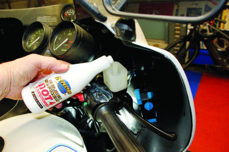 hand pouring white bottle into white reservoir near black handle bar